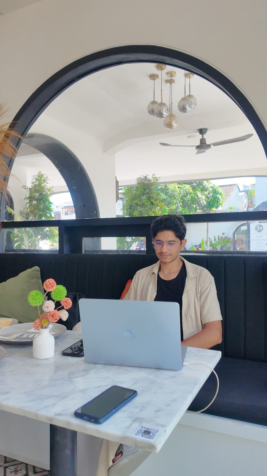 Working on a laptop under a stone arch cafe, side profile
